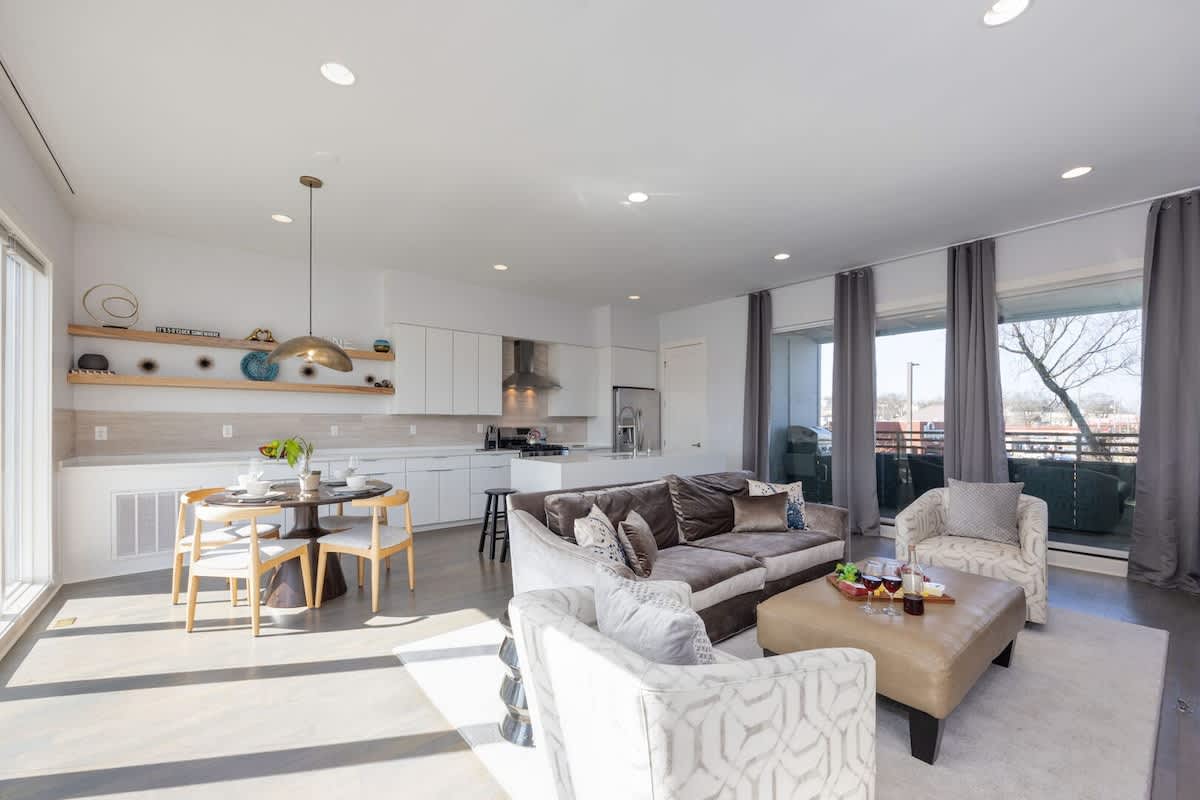 Bright open floor living space featuring designer furnishings, a smart TV, a fireplace, and access to a private balcony. (2nd Floor)