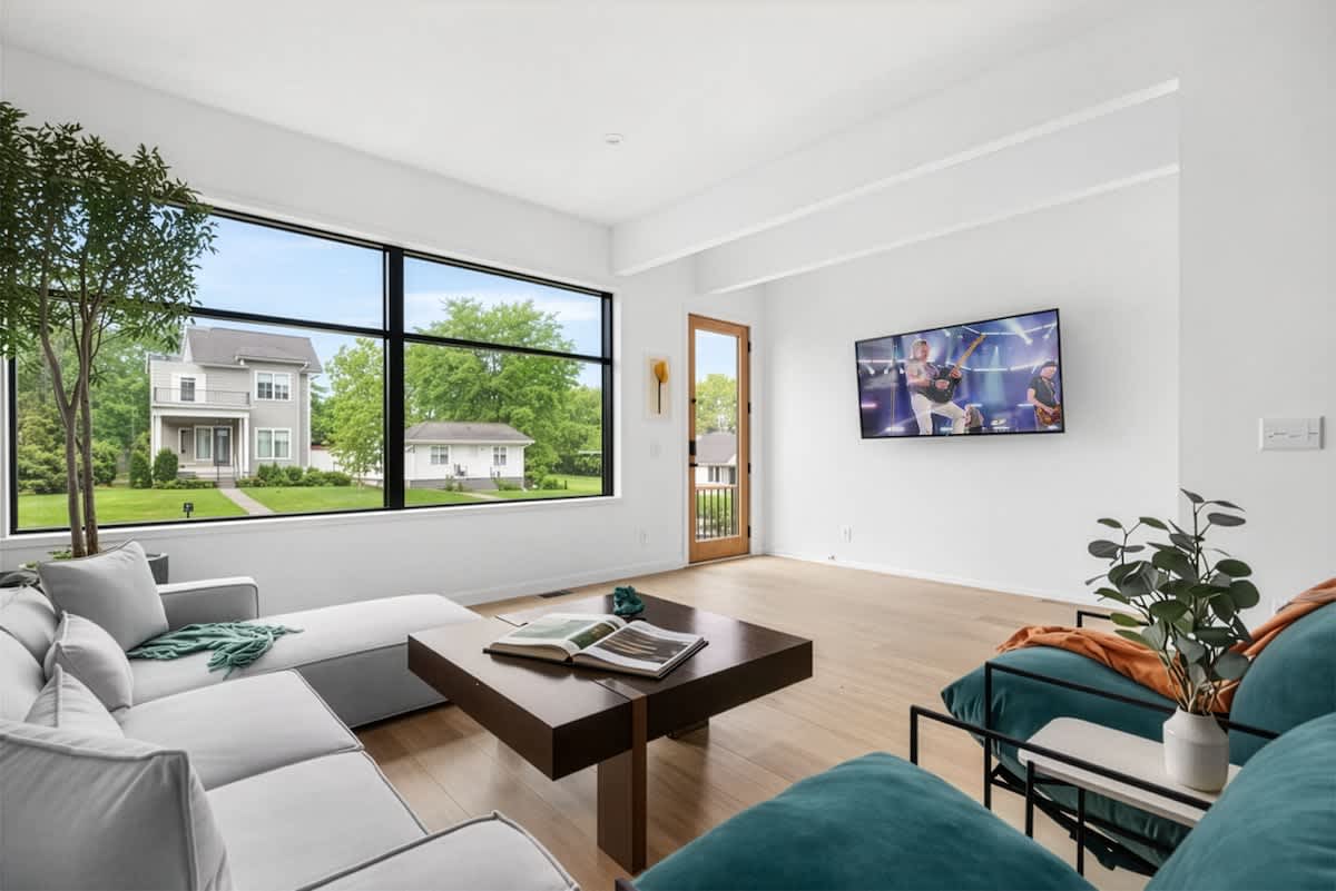 Bright and modern open concept living room with oversized windows, a comfortable sectional, bold artwork, and a Smart TV. (1st Floor)