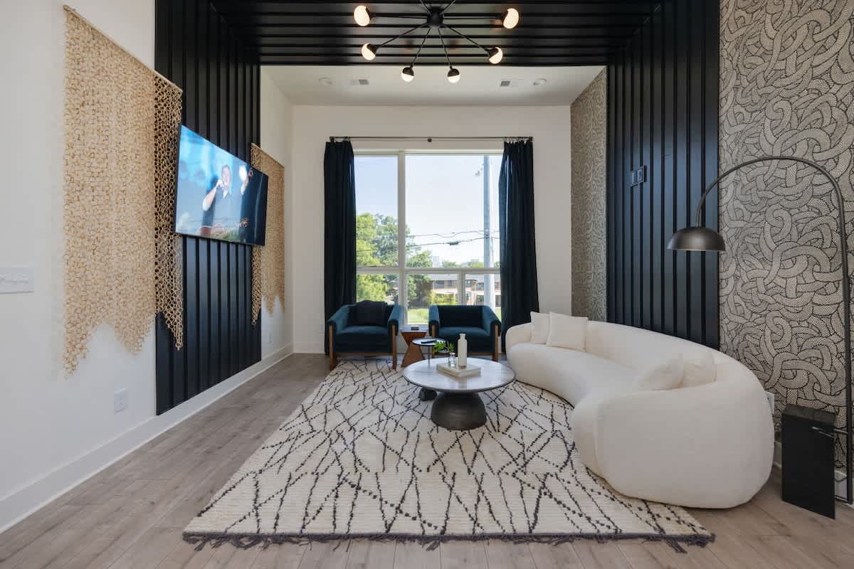 Unit 1: (1st Floor) Modern trendy living room adorned in designer furnishings and decor with sky-high ceiling, large windows and a Smart TV for entertainment.