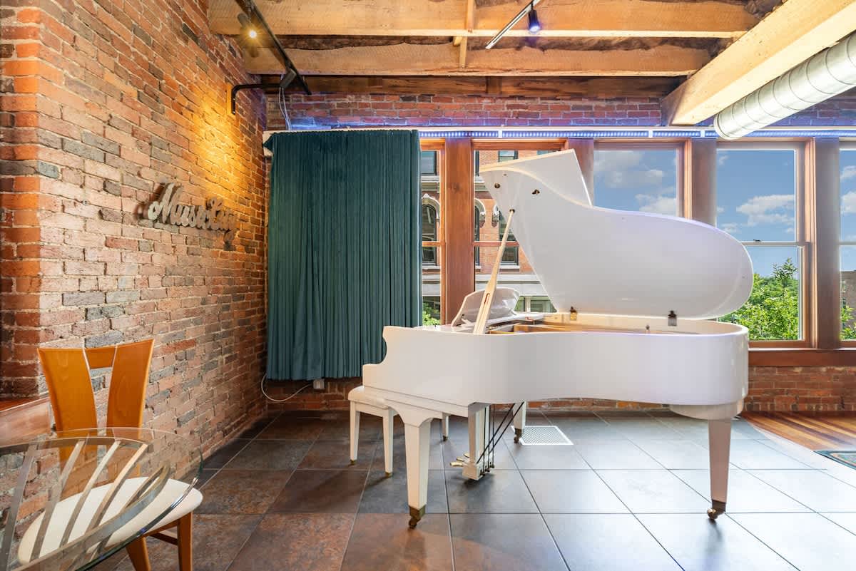 Unit 2: Main Living Area featuring designer furnishings, TV Projector, piano, electric guitars, and electronic Window Curtains
