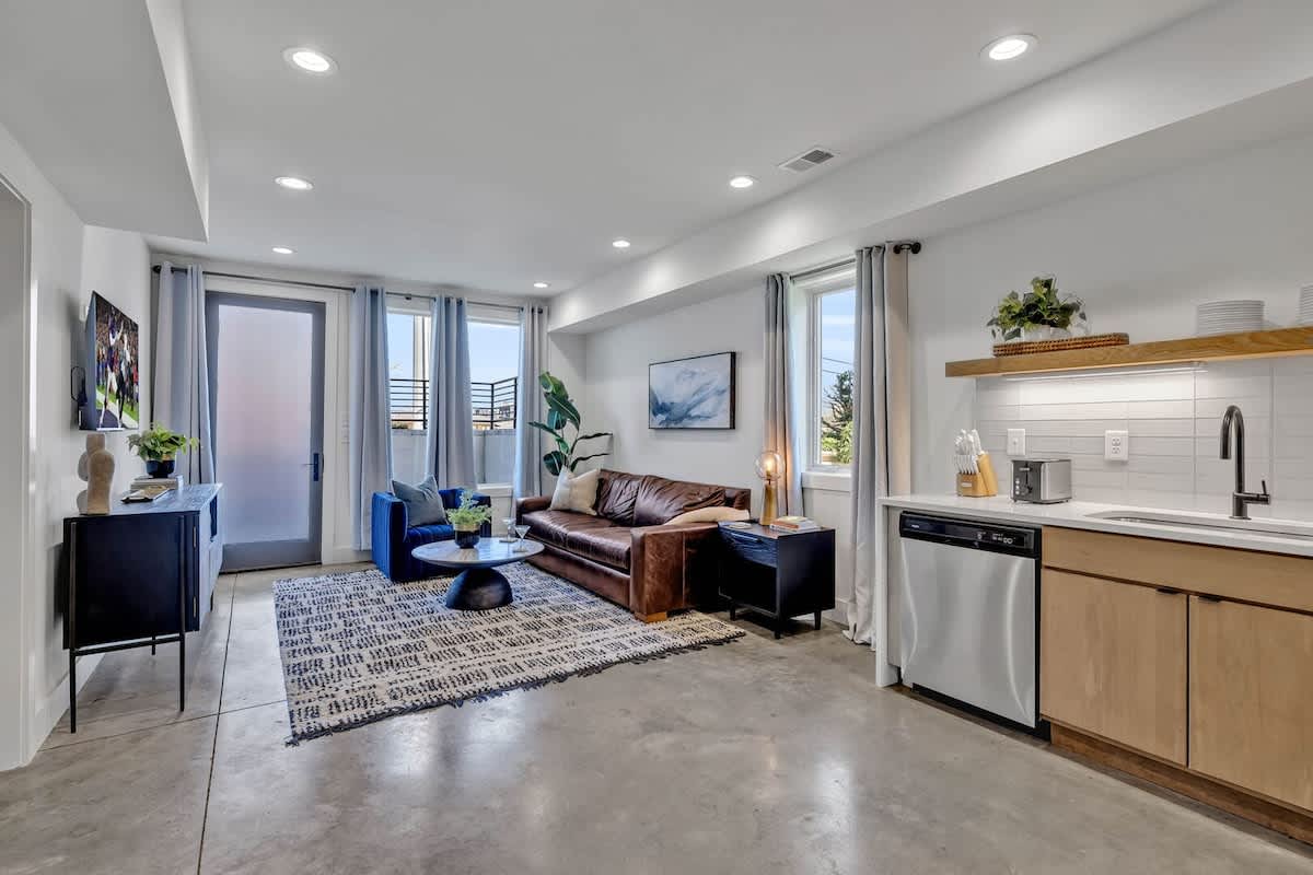 Open-concept living space featuring a comfortable sectional with a Smart TV for entertainment and a fully equipped kitchen stocked with all culinary essentials and stainless steel appliances.