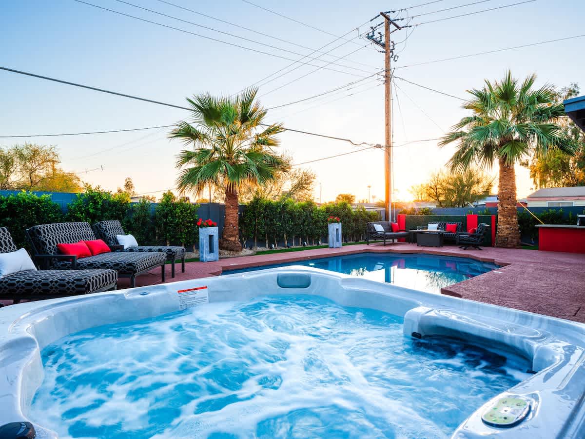 Outdoor patio with heated optional pool, hot tub, fire pit, outdoor dining area, BBQ, and cornhole.