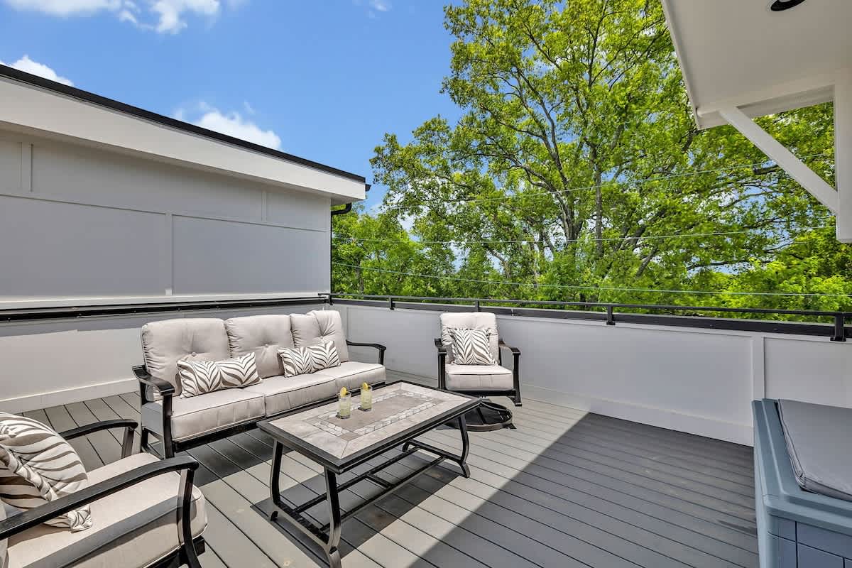 (Unit 3) 4th Floor: Private rooftop patio featuring outdoor furnishings for lounging and a Smart TV for entertainment surrounded by beautiful neighborhood views.