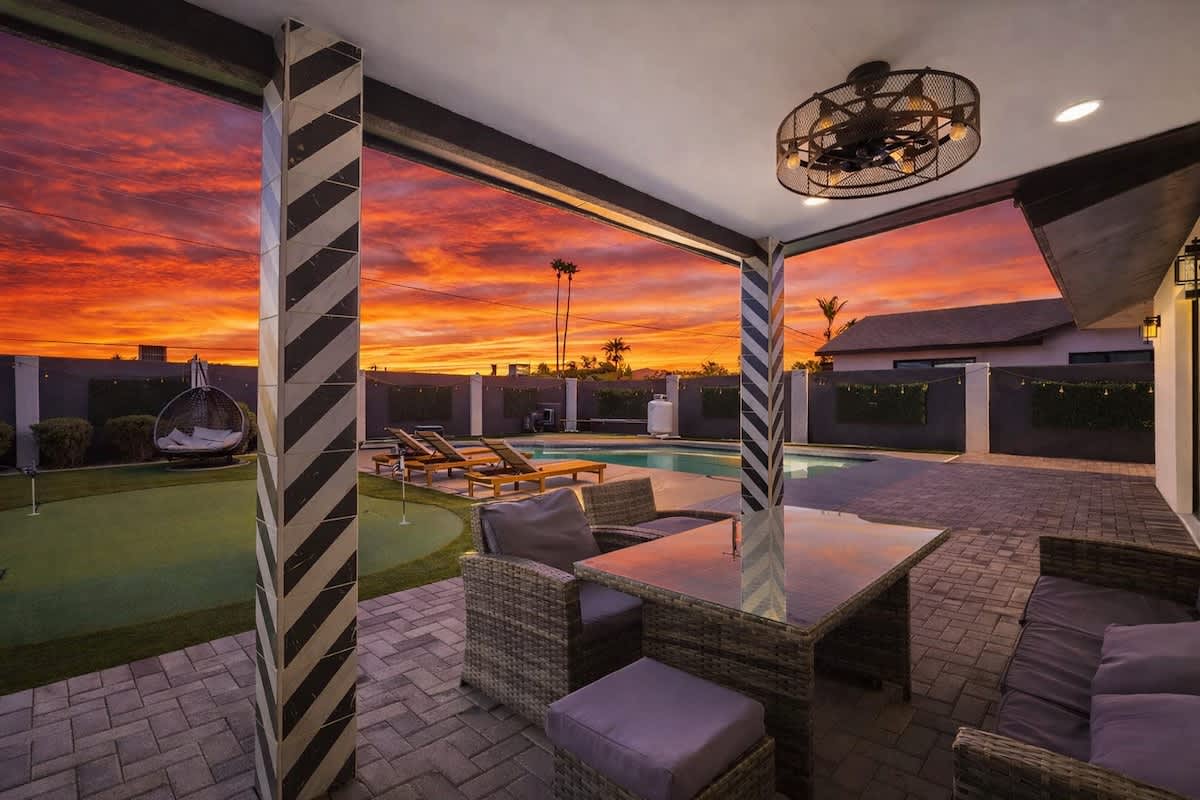 Private backyard featuring a sparkling pool, sun loungers, mini golf, and a covered patio with outdoor seating, and a BBQ grill.