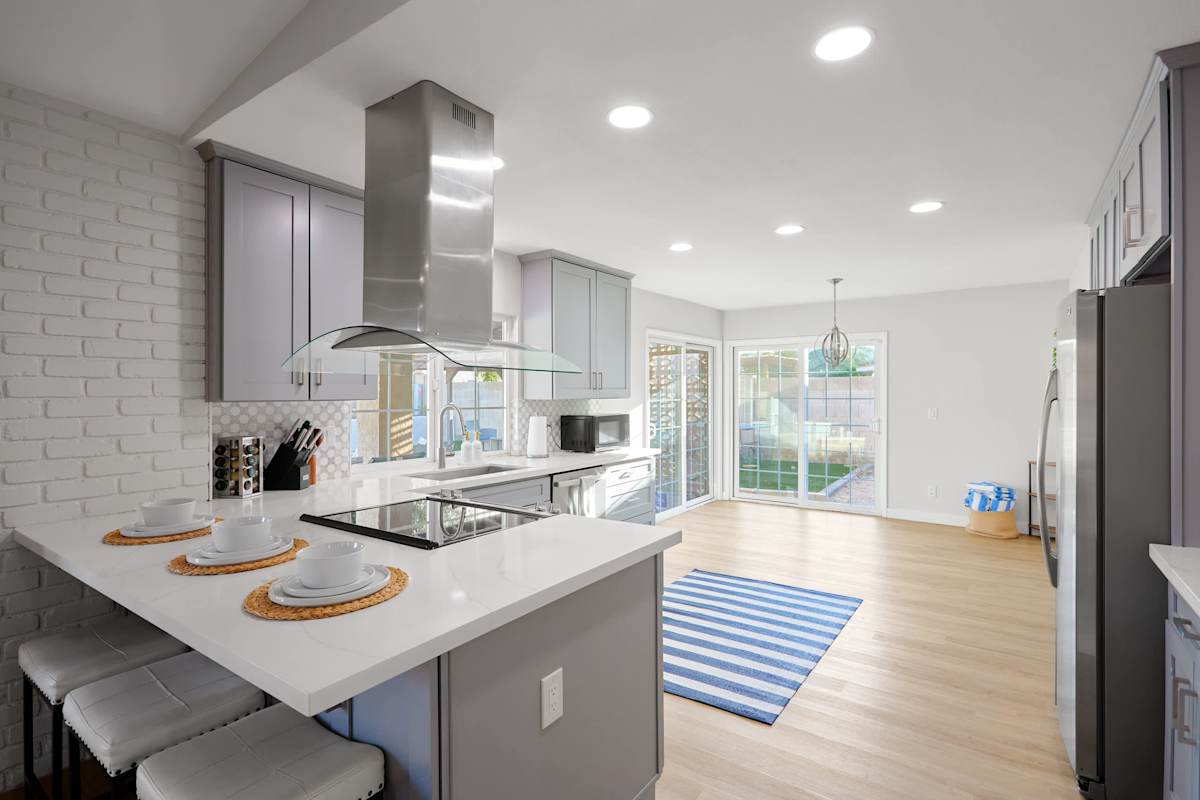 Kitchen comfort meets full function with a spacious island seating three, stainless steel appliances, and a sleek range hood, plus a coffee bar.