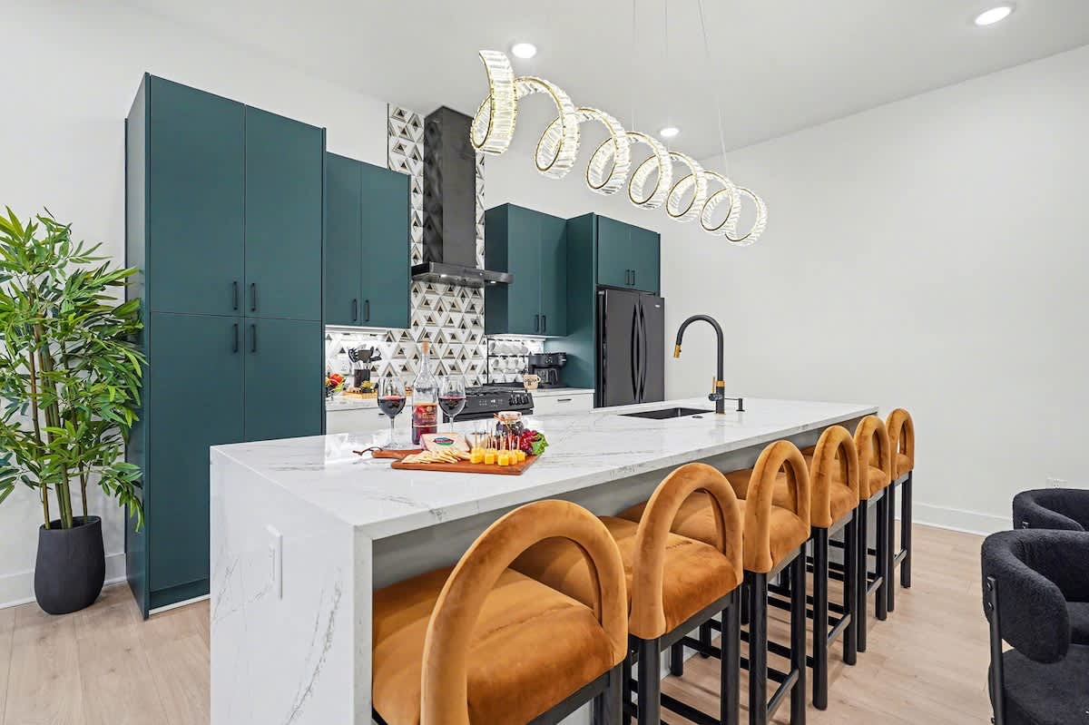 2nd Floor: Fully equipped kitchen with green cabinetry, marble countertops, black appliances, and a striking waterfall island offering bar seating for 6.