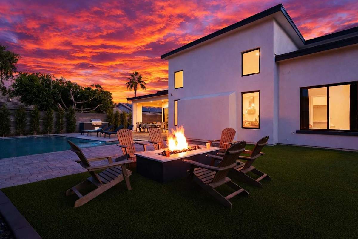 Stunning private yard with sparkling pool, sun loungers, lawn space, covered patio with lounge area, covered outdoor dining area, fire pit, and built-in BBQ grill!