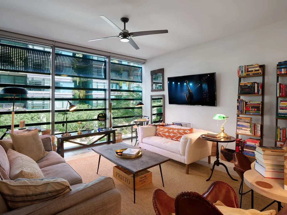 Bright and open living area with a smart TV, cozy furnishings, workstation, and access to a private patio.
