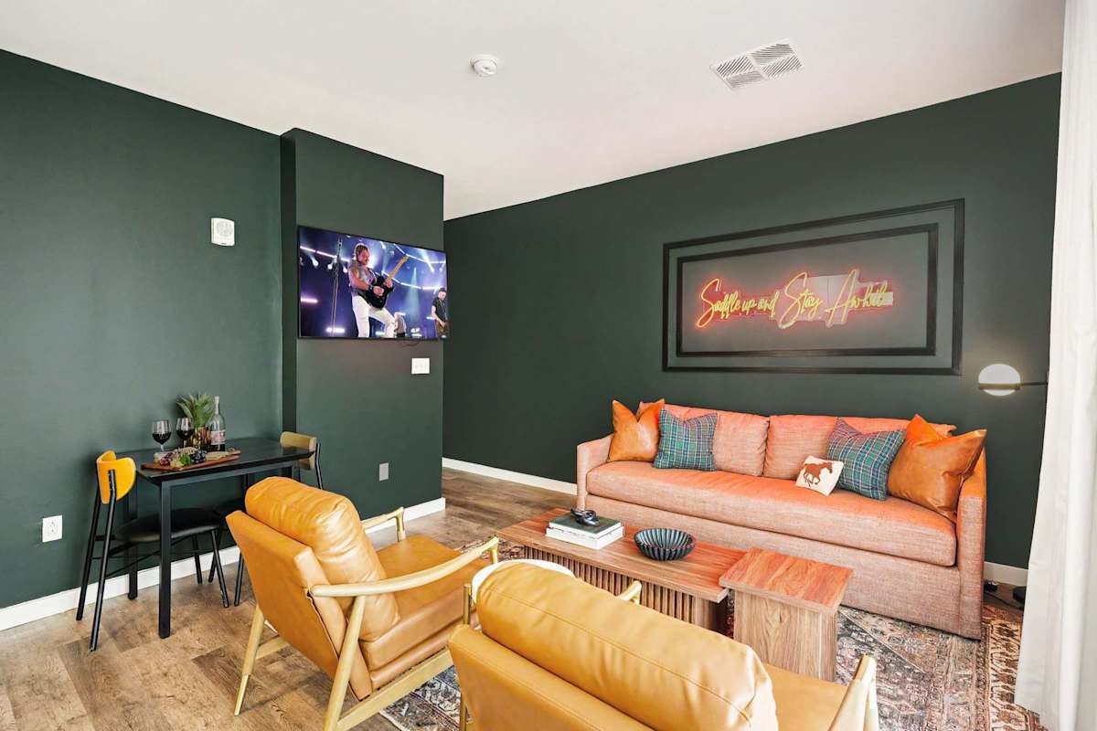 Bright and open living area featuring a smart TV, plush furnishings, and access to the private balcony. Connects to the dining area and kitchen.