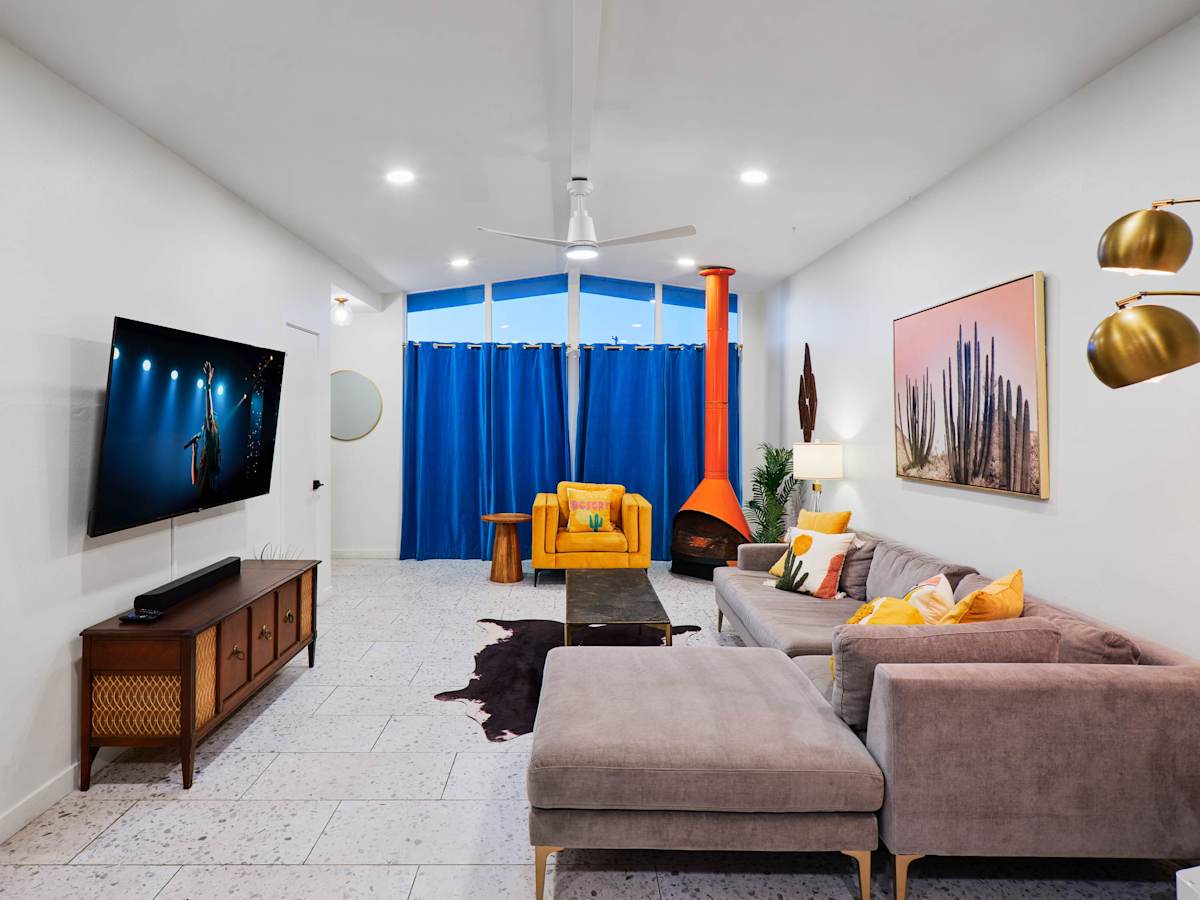 Bright, open living room blending mid-century charm with modern comfort, featuring a Smart TV, iconic fireplace, and spacious seating for gathering and unwinding.