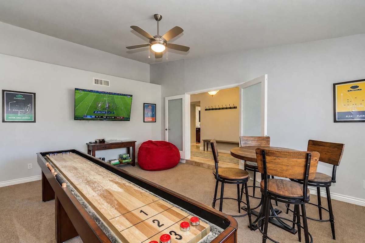 Game room with smart TV, shuffle board, high top table for 4, ceiling fan, and board games