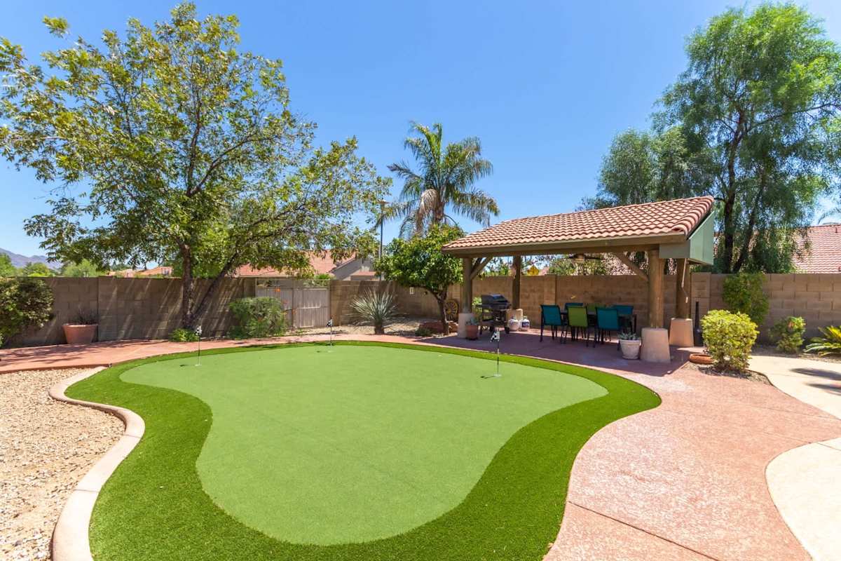 Spacious private yard with sparkling pool, spa, covered patio with outdoor dining area, BBQ grill, and putting green.