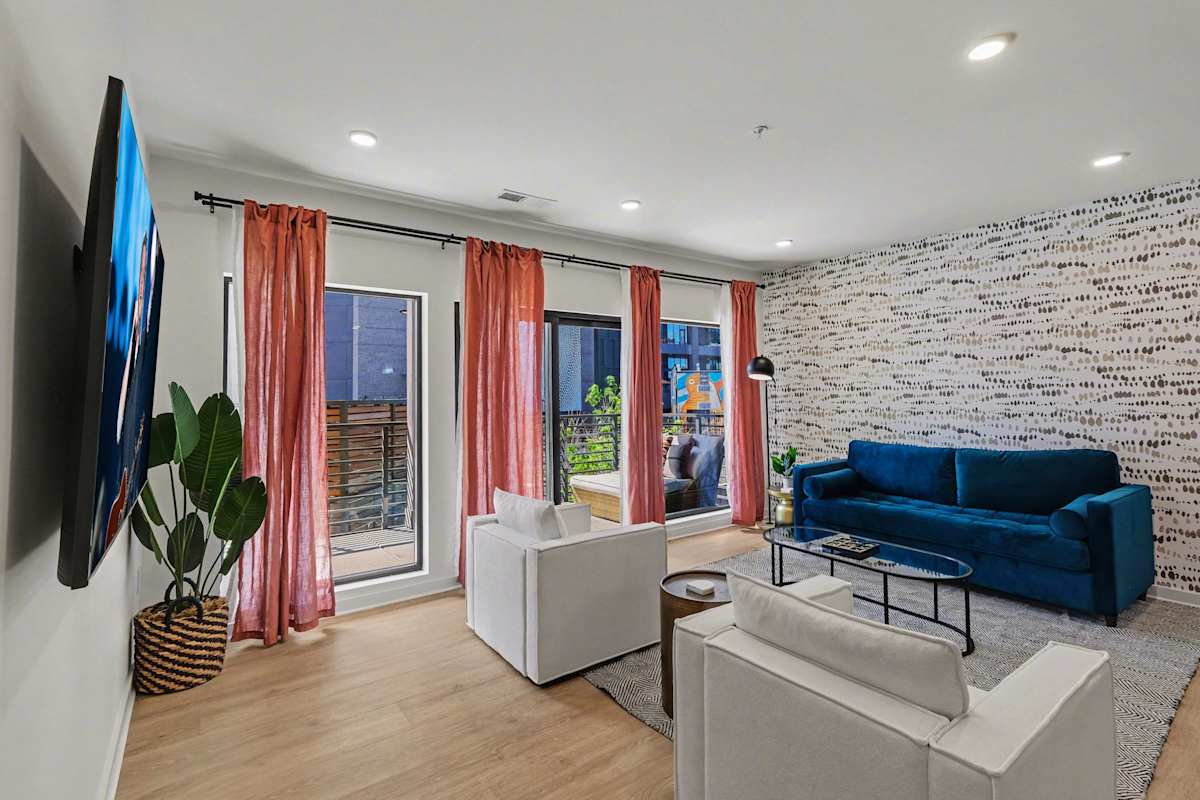 Bright open living space featuring smart flat-screen TV, designer furnishings, and patio entrance with pool view.