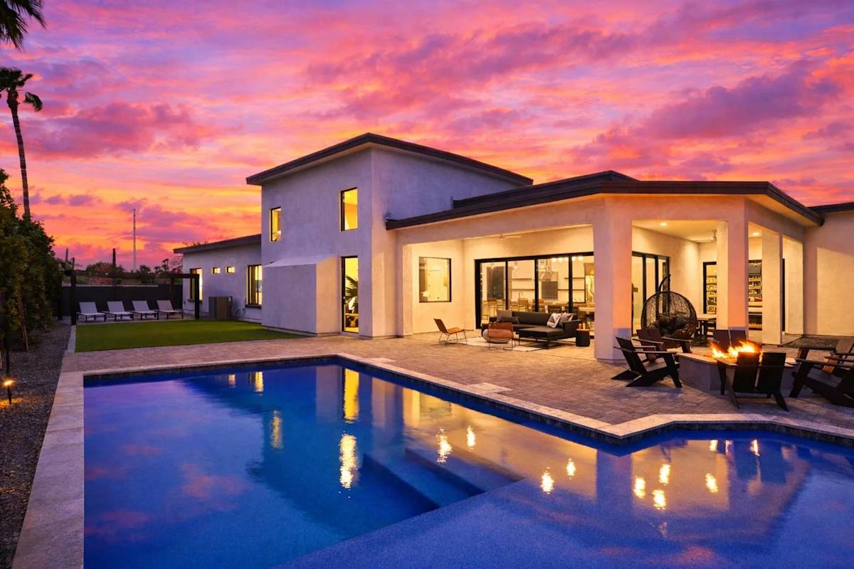 Stunning private yard with sparkling pool, sun loungers, lawn space, covered patio with lounge area, covered outdoor dining area, fire pit, and built-in BBQ grill!