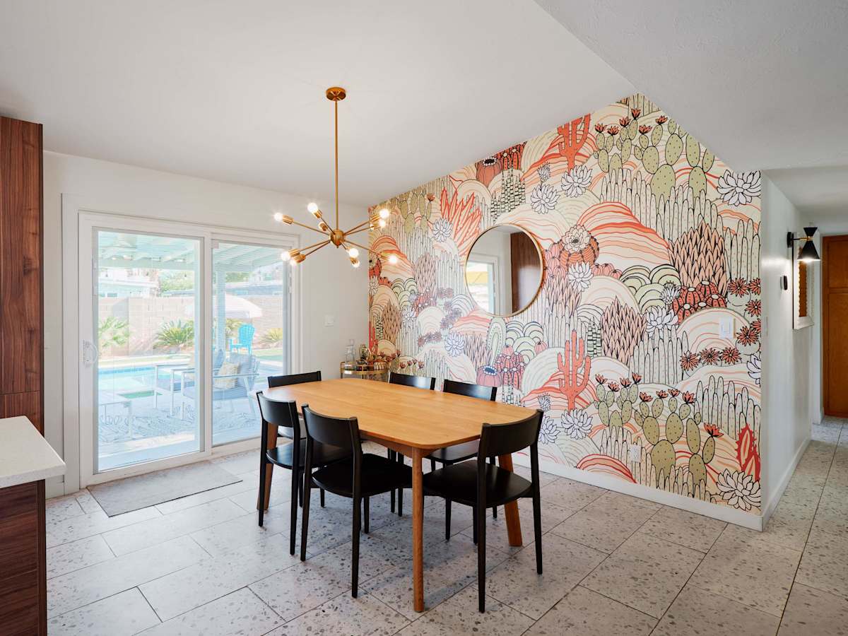 Dining area with seating for 6, a striking desert-inspired feature wall, and direct access to the poolside patio.