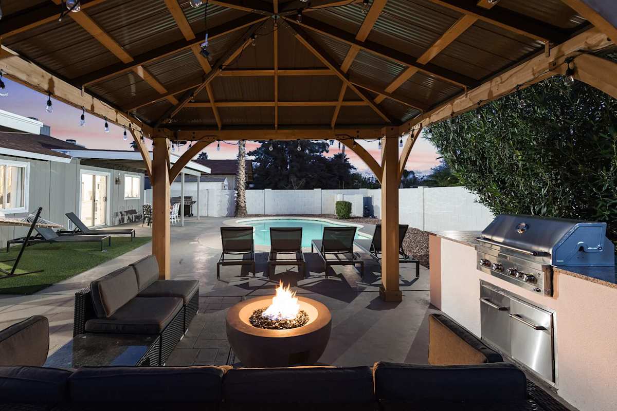Backyard with large pool, sun loungers, covered patio with 6 person outdoor dining table, and a covered gazebo with bistro lights, outdoor furnishings, fire-pit, and BBQ.