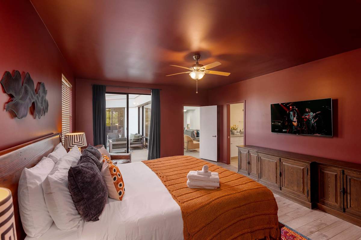 Spacious primary suite with a King bed, Smart TV, cozy sitting area, private balcony access, and an en-suite bathroom for added privacy and comfort.