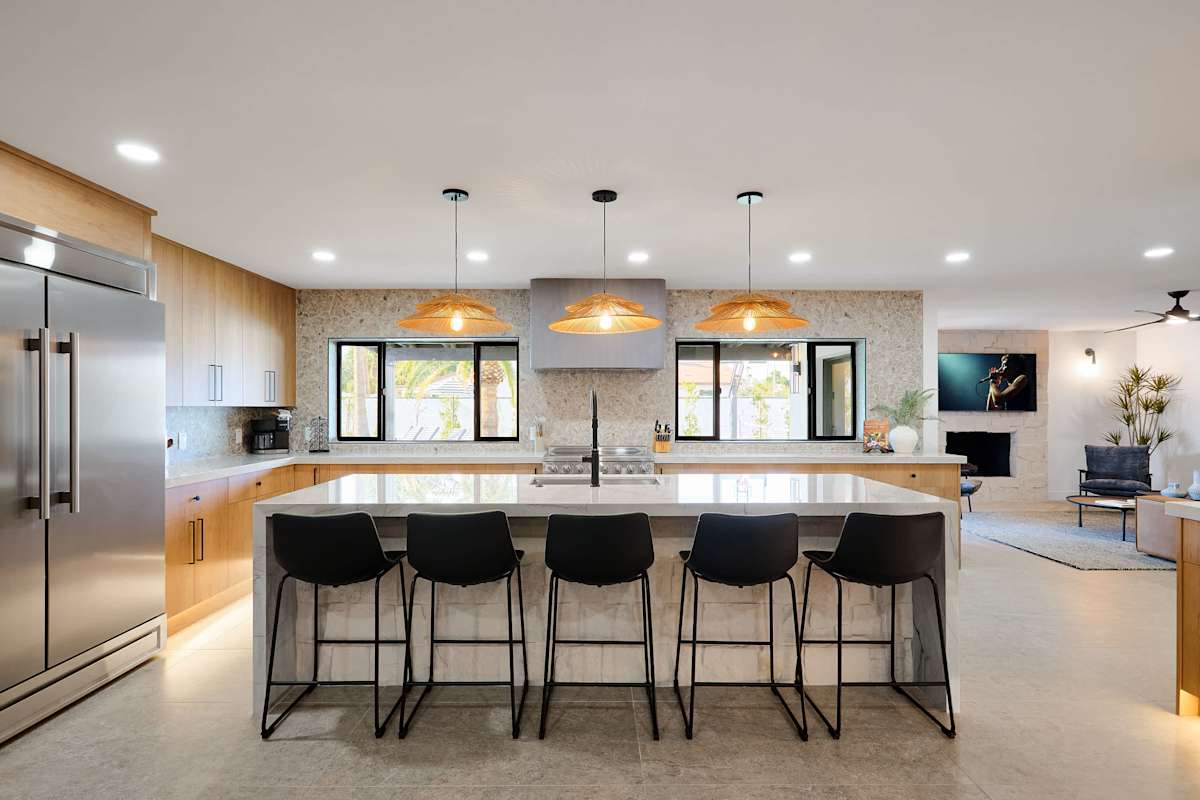 Sleek open concept kitchen with stainless steel appliances, large island with breakfast bar seating for 5, coffee bar with espresso machine, and fully equipped with your basic cooking essentials.
