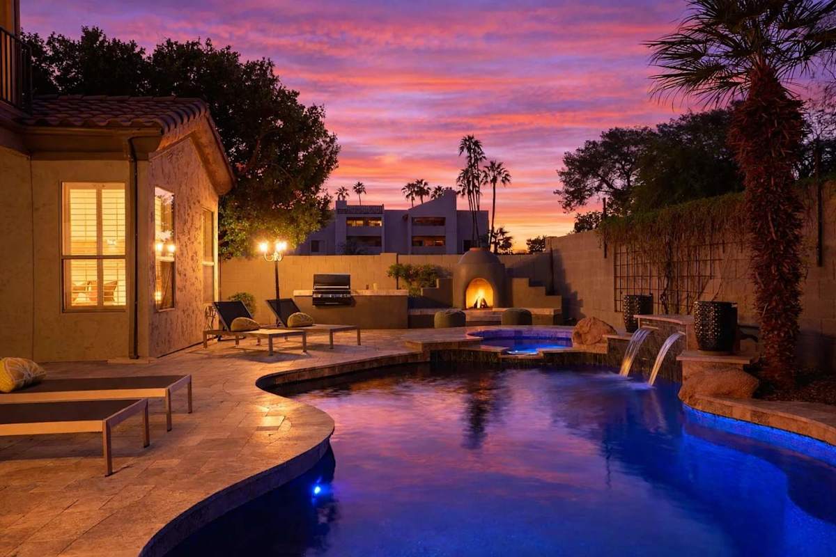 Backyard oasis featuring a covered patio w/ dining, sparkling pool with spa, plus a built-in grill and fireplace perfect for outdoor gatherings.