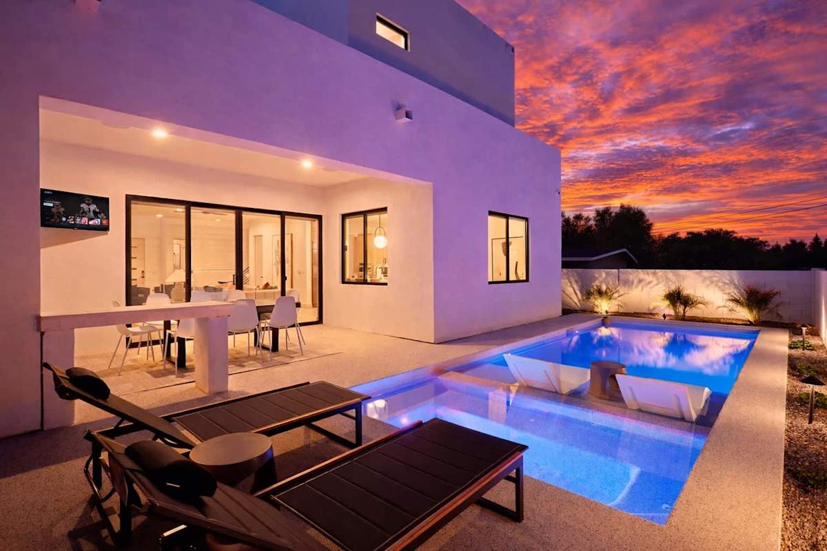 Outdoor oasis featuring a sparkling, heated optional pool & hot tub, multiple seating areas, lounge chairs, BBQ grill, firepit, and outdoor smart TV.