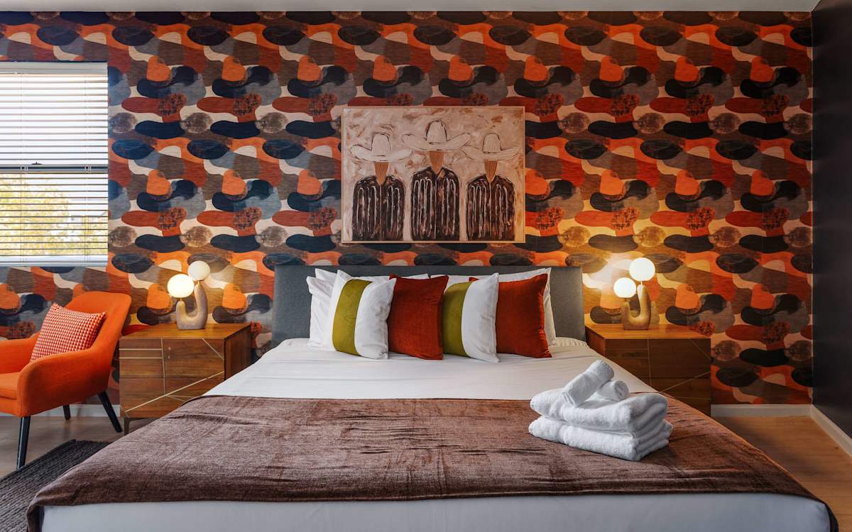 Primary bedroom featuring a King bed, Smart TV, cozy sitting area, private balcony access, and an en-suite bathroom for a relaxing retreat.