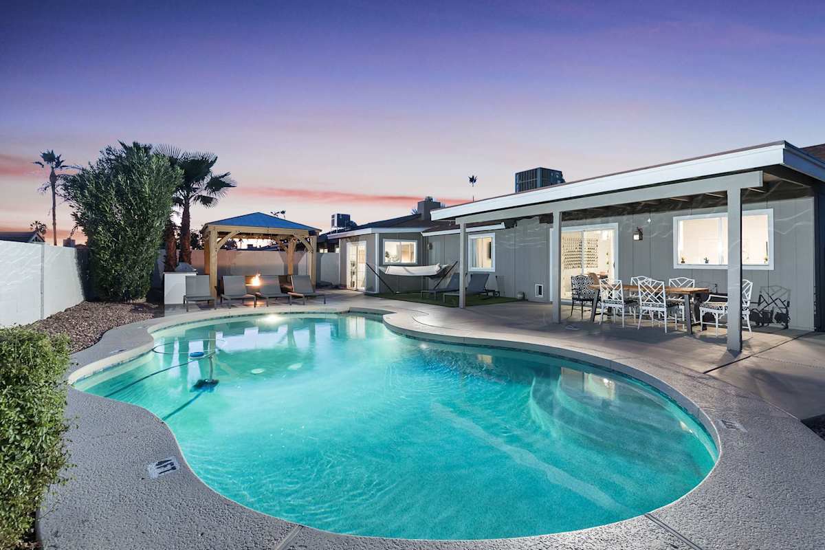 Backyard with large pool, sun loungers, covered patio with 6 person outdoor dining table, and a covered gazebo with bistro lights, outdoor furnishings, fire-pit, and BBQ.