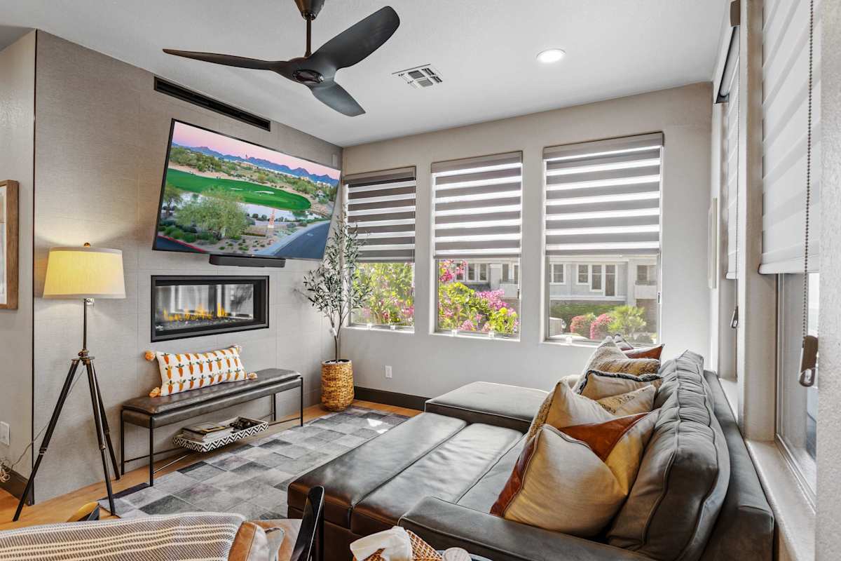 Relax in this bright, stylish living area with a plush sectional, cozy fireplace, oversized TV, and sun-filled windows.