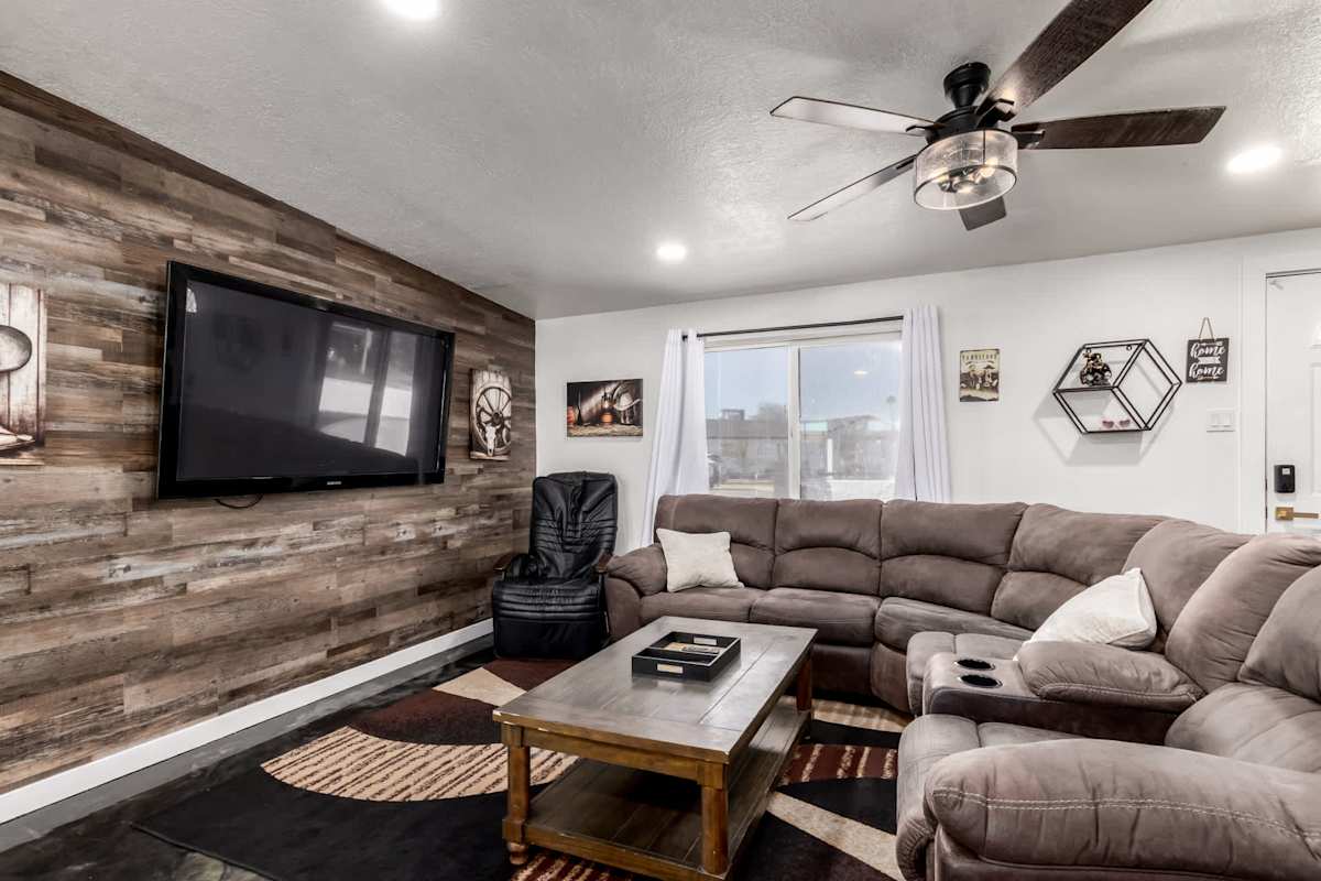 The living room's Western charm shows in the reclaimed wood accent wall and vintage Tombstone mural, framing a plush sectional and smart TV perfect for group movie nights.