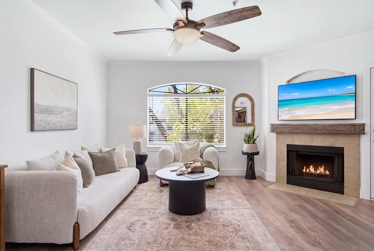 The living room's gas fireplace sets a cozy glow beside a mounted smart TV, with an open flow into the kitchen and dining area for easy gathering.