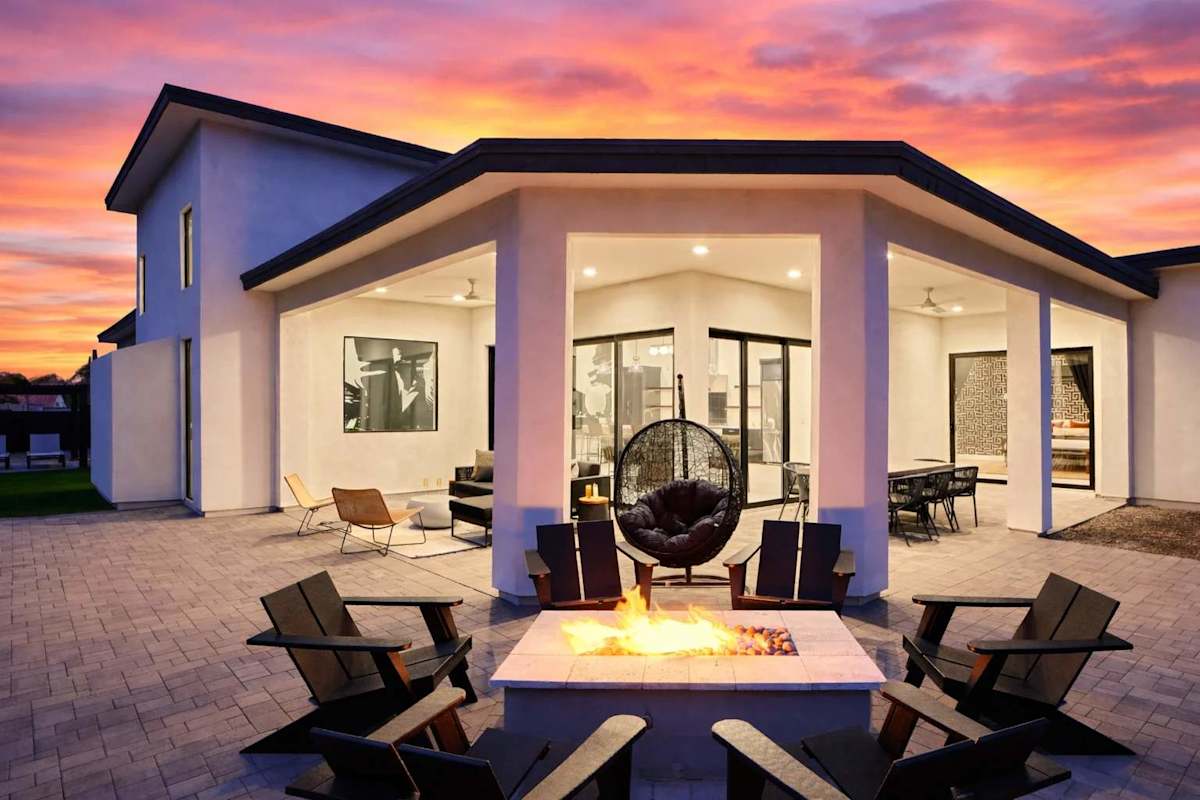 Stunning private yard with sparkling pool, sun loungers, lawn space, covered patio with lounge area, covered outdoor dining area, fire pit, and built-in BBQ grill!