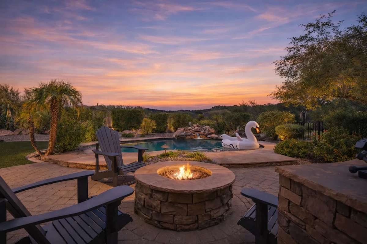 Beautiful backyard with a covered patio, sparkling pool, shaded seating, dining area, grill, and grass area.
