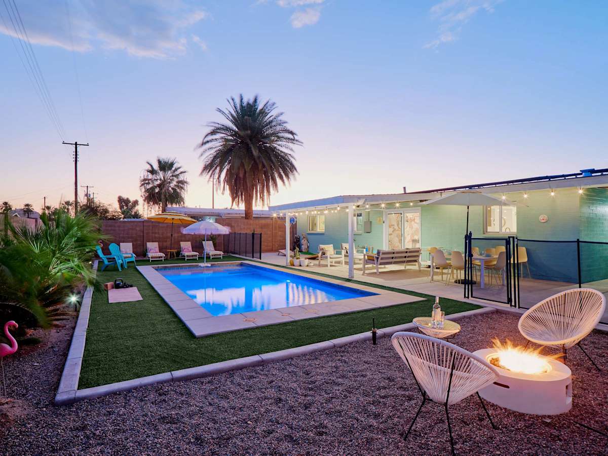 Private backyard oasis featuring a sparkling pool, fire pit lounge, shaded outdoor dining, poolside seating, cornhole, basketball, and a putting green.