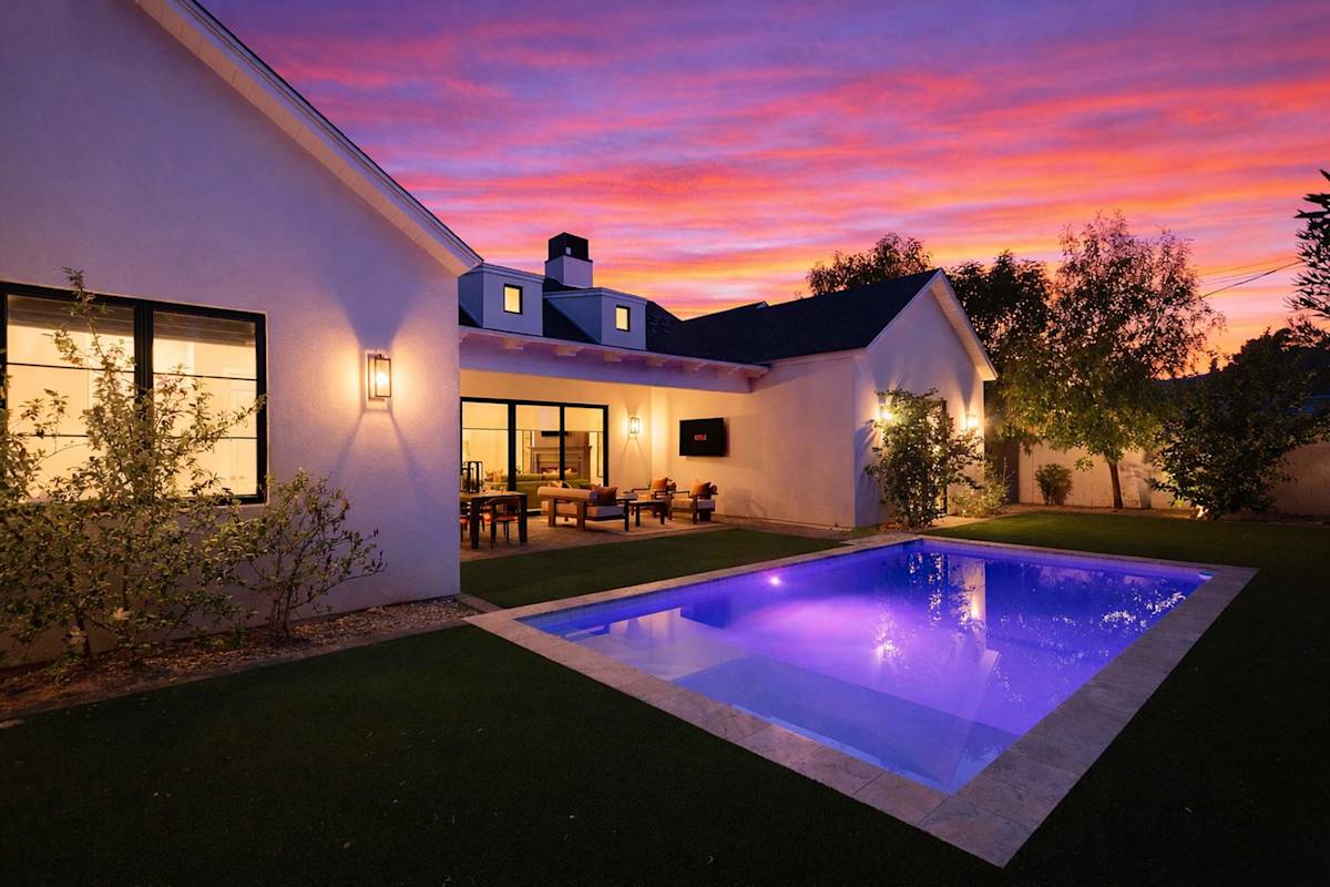 Private backyard with a sparkling pool and a covered patio with an outdoor dining area, outdoor seating, and a smart TV.