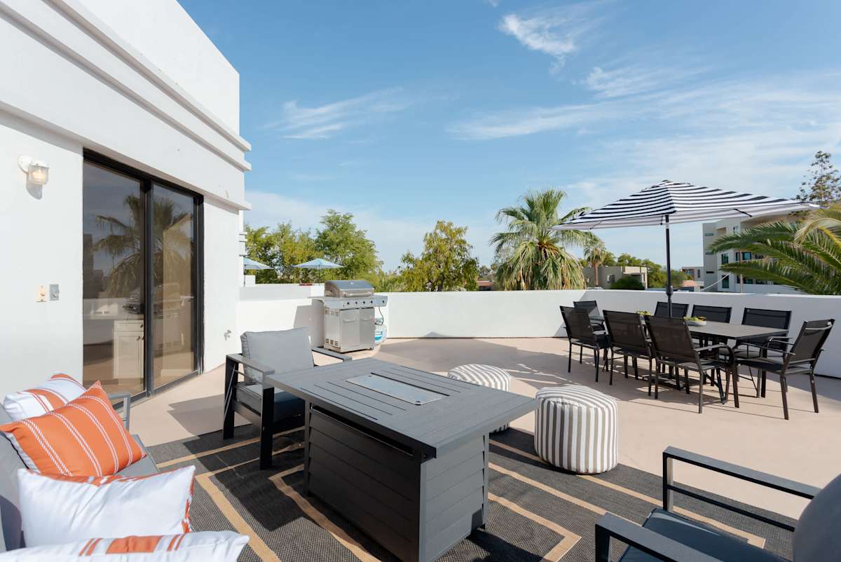 Expansive private balcony featuring lounge seating with built in fire pit table, a BBQ grill, outdoor dining table for 8, and plenty of space to soak up the Scottsdale sunshine or unwind in the fresh
