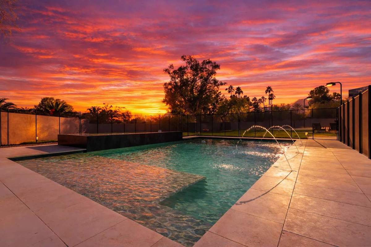 Expansive backyard paradise with a full-size basketball court, sprawling lawn, fire pit lounge, sparkling pool with oversized spa, outdoor dining for 16, and both covered and open-air patios filled wi