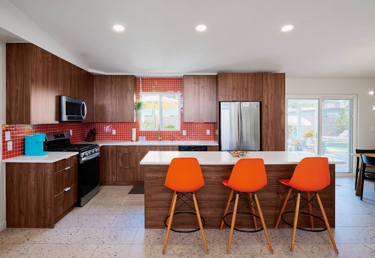 Spacious kitchen featuring stainless steel appliances, generous counter space, and a large island with seating for 3, perfect for gathering over meals and conversation.