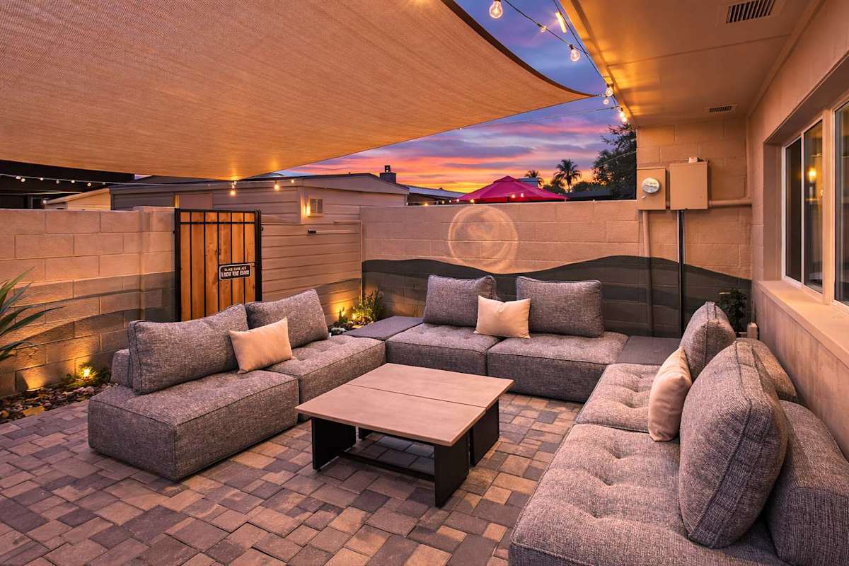 Private patio featuring a comfortable outdoor lounge, dining area, BBQ grill, and a desert-themed mural that adds character to the space.