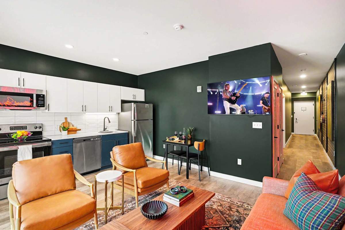 Bright and open living area featuring a smart TV, plush furnishings, and access to the private balcony. Connects to the dining area and kitchen.