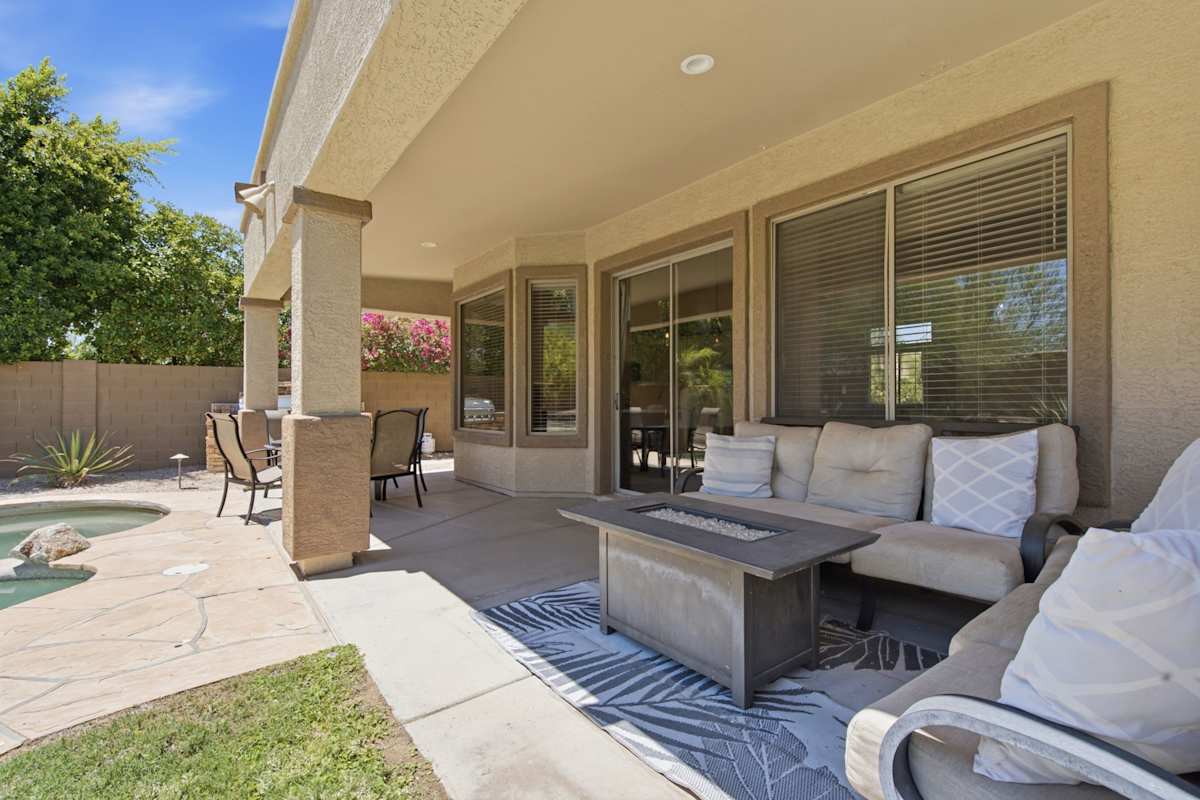 This backyard centers around a pebble-finish pool and spa, with a covered patio, fire pit lounge, dining area, and built-in stone BBQ for easy outdoor entertaining.