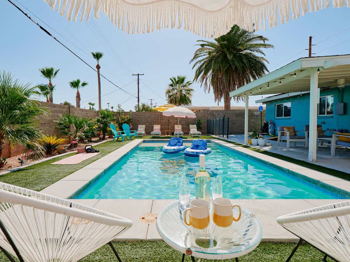 Private backyard oasis featuring a sparkling pool, fire pit lounge, shaded outdoor dining, poolside seating, cornhole, basketball, and a putting green.
