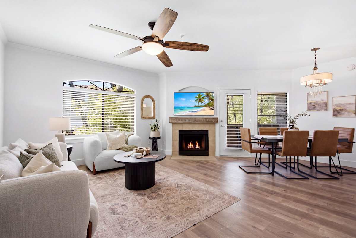 The living room's gas fireplace sets a cozy glow beside a mounted smart TV, with an open flow into the kitchen and dining area for easy gathering.