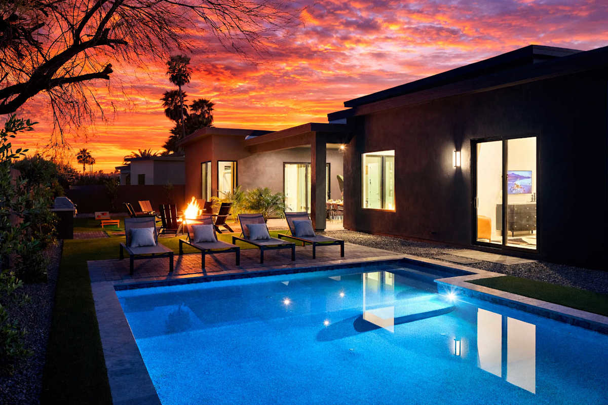 Unit 2: Resort-like backyard with a covered patio offering outdoor dining, a sparkling blue heated pool with sun loungers, yard games, a BBQ grill and a fire pit.